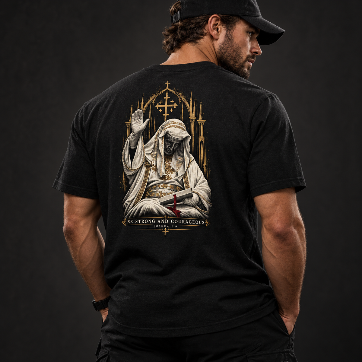 Man in a black cap wearing the Built Daily King Baldwin tee, back view: Baldwin IV in white robes and iron mask, BE STRONG AND COURAGEOUS, Joshua 1:9