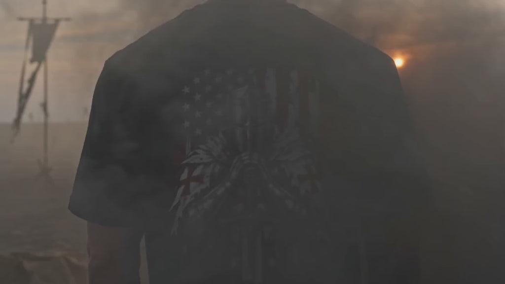 Video: a man in the Psalm 33:12 Knight Tee walks onto a smoky battlefield at sunset, showing the praying knight and American flag design on the back